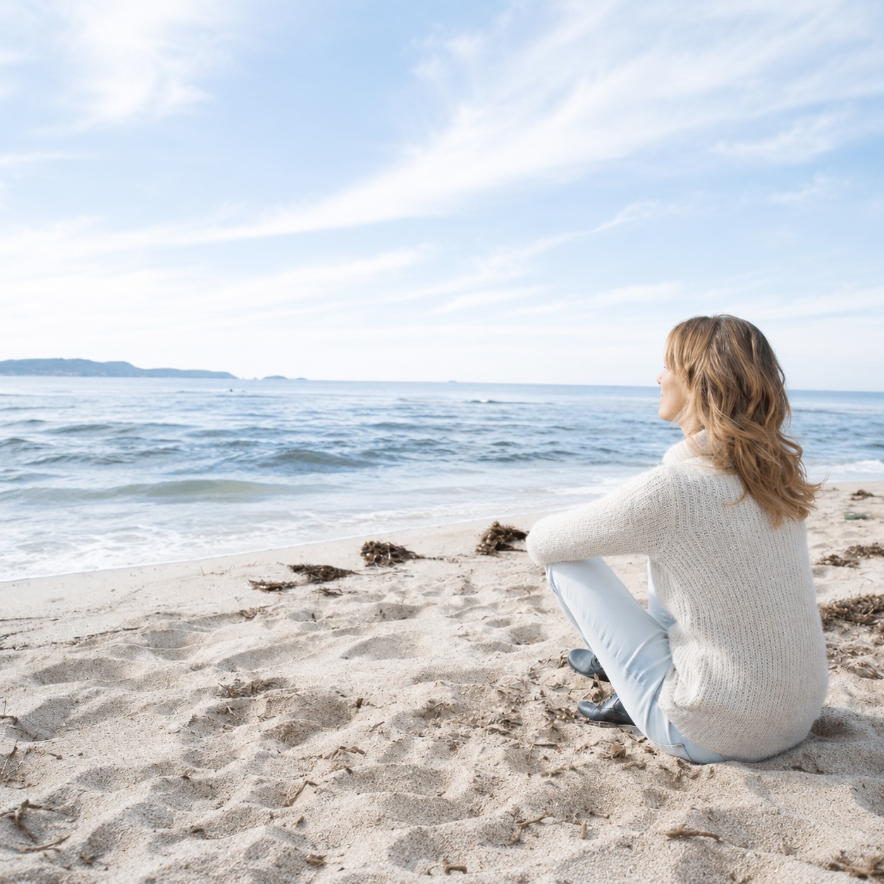 Person sitzt am Strand und blickt ruhig auf das Meer als Symbol für neue Freiheit und Hypnose bei Phobien in Cuxhaven.